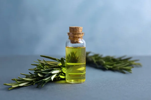 Garrafa com óleo essencial de alecrim e erva fresca na mesa — Fotografia de Stock