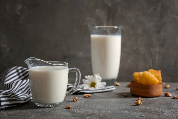 Jug with milk and nuts on grey table — Stock Photo, Image