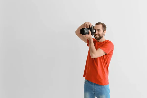 Junger Fotograf mit professioneller Kamera auf weißem Hintergrund — Stockfoto