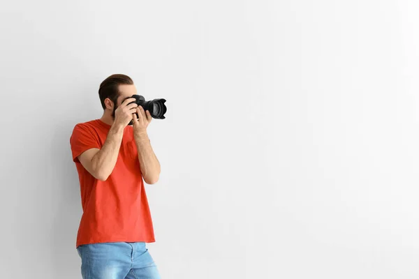 Młody fotograf z profesjonalnym aparatem na białym tle — Zdjęcie stockowe