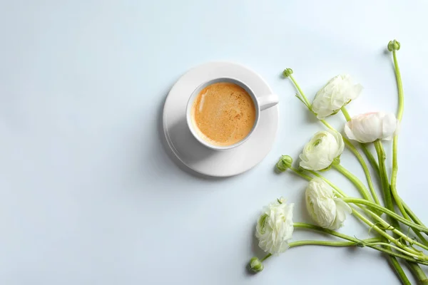 Чашка горячего кофе и красивые цветы Ранункулус на белом фоне — стоковое фото