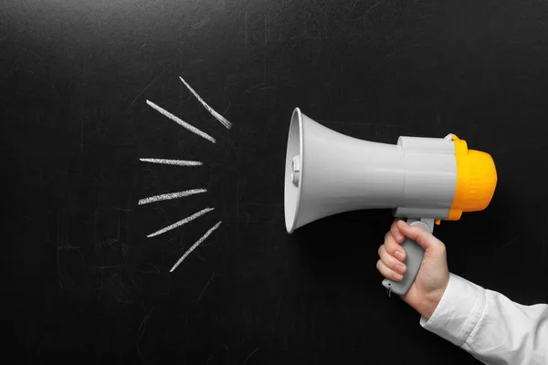 Man holding megaphone near chalkboard — Stock Photo, Image