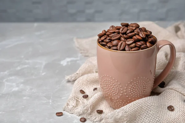 Copo de cerâmica com grãos de café na mesa — Fotografia de Stock