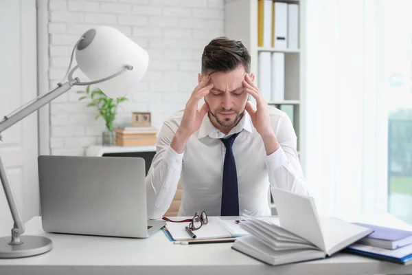 Uomo che soffre di mal di testa mentre è seduto a tavola in ufficio — Foto Stock