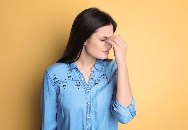 Jonge vrouw lijden aan hoofdpijn op kleur achtergrond — Stockfoto