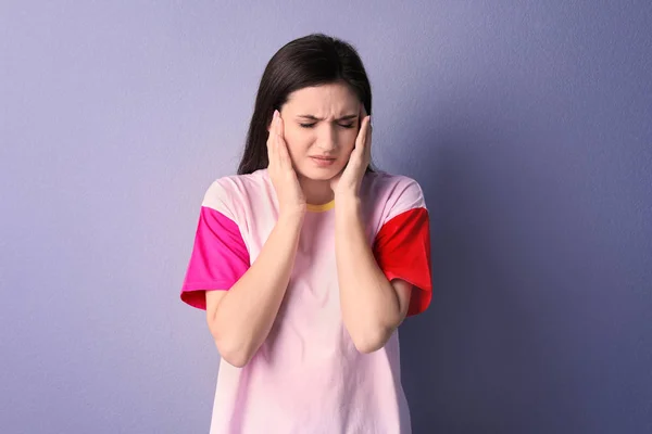 Jonge vrouw lijden aan hoofdpijn op kleur achtergrond — Stockfoto