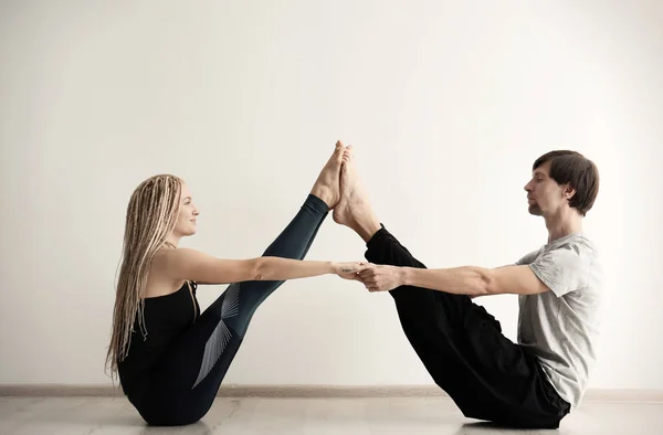 Young man and woman practicing yoga indoors — Stock Photo, Image