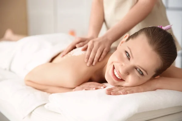 Hermosa mujer joven teniendo masaje con exfoliante corporal en el salón de spa — Foto de Stock