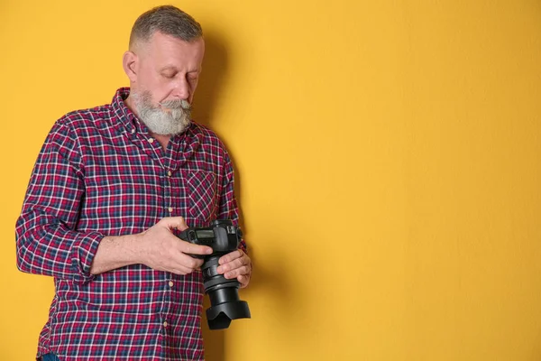 Mature male photographer with camera on color background — Stock Photo, Image