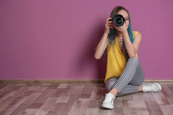 Jonge vrouwelijke fotograaf met de camera in de buurt van kleur muur — Stockfoto