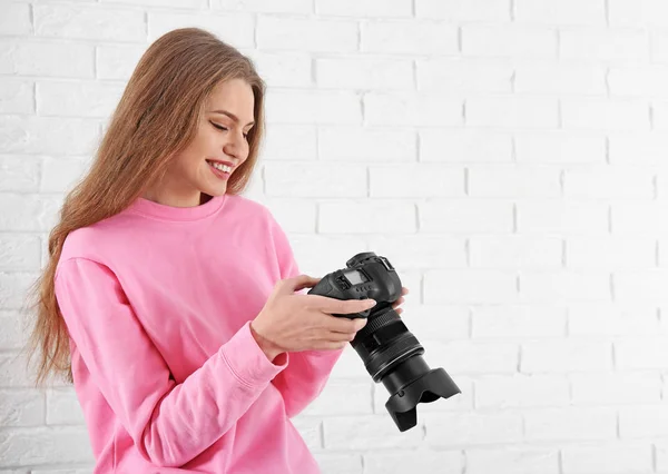 Female photographer with camera on brick background — Stock Photo, Image