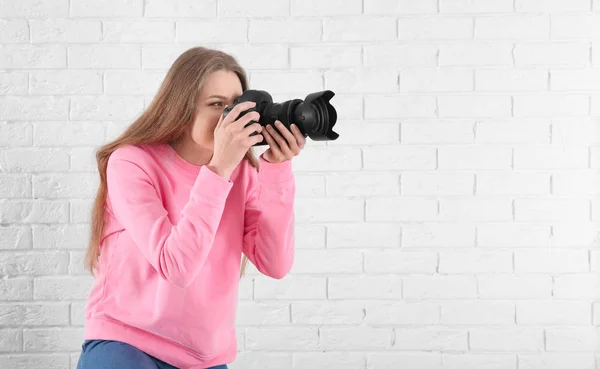 Fotógrafo femenino con cámara sobre fondo de ladrillo — Foto de Stock