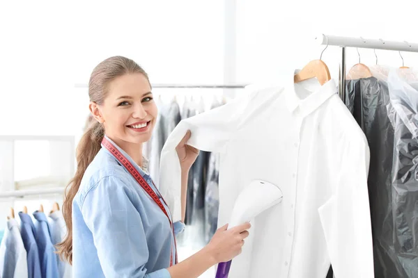 Junge Frau dampft Hemd bei Reinigungsfirma — Stockfoto