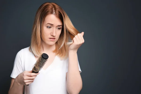 Молодая женщина с проблемой выпадения волос на сером фоне — стоковое фото
