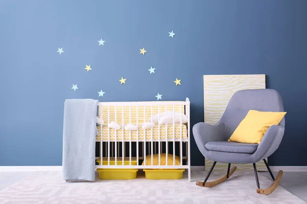 Интерьер детской комнаты с кроваткой и креслом-качалкой у стены — стоковое фото