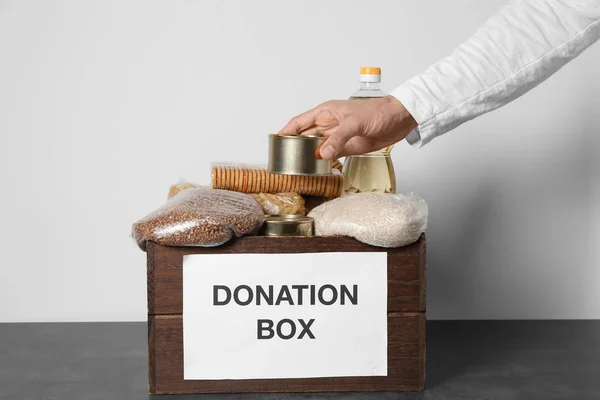 Hombre voluntario recogiendo comida en caja de donación —  Fotos de Stock