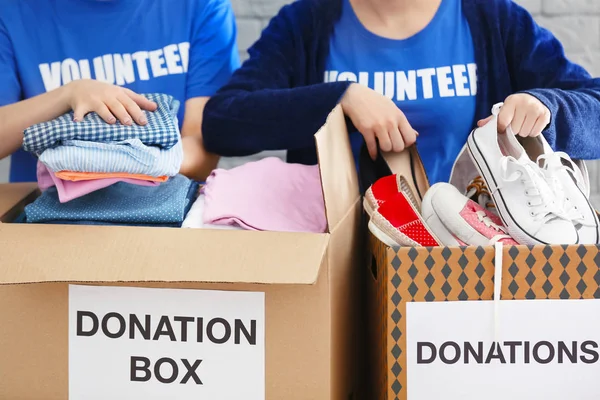 女性志愿者收集衣服和鞋子到捐赠箱室内 — 图库照片