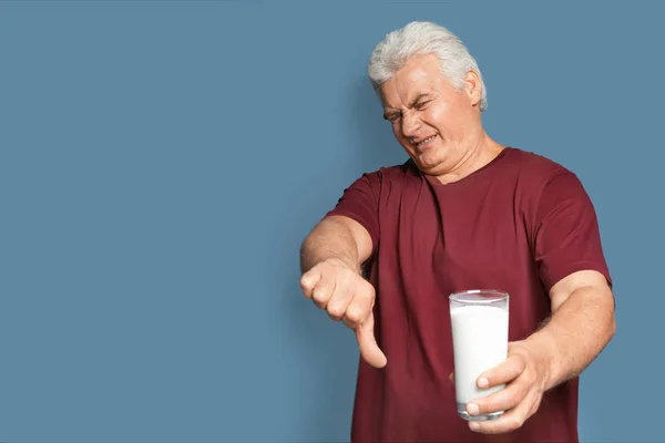 Älterer Mann mit Milchallergie hält Glas Milch auf farbigem Hintergrund — Stockfoto