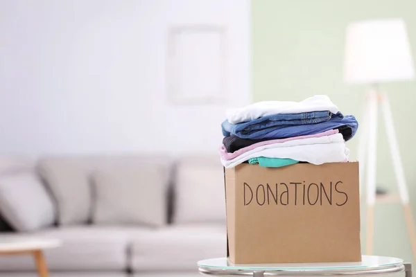 Caja de donación con ropa en la mesa en el interior — Foto de Stock