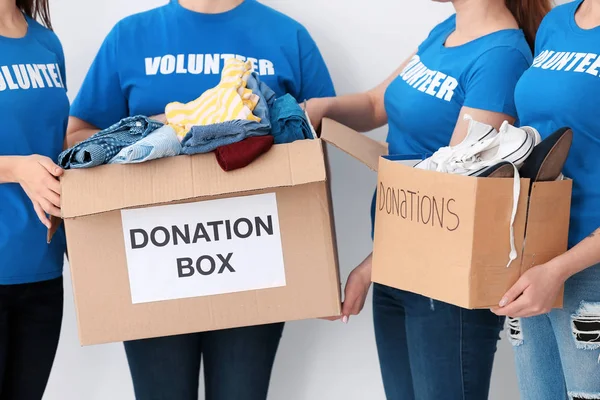 Equipo de voluntarios con cajas de donación sobre fondo claro —  Fotos de Stock