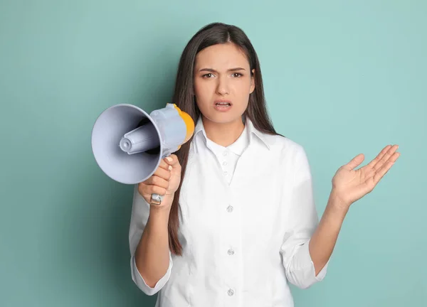 Jovem médica com megafone sobre fundo de cor — Fotografia de Stock