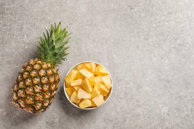 Bütün ve dilimlenmiş taze ananas gri arka plan üzerinde