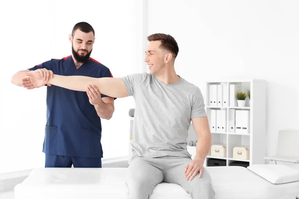 Fysiotherapeut werken met jonge mannelijke patiënt in kliniek — Stockfoto