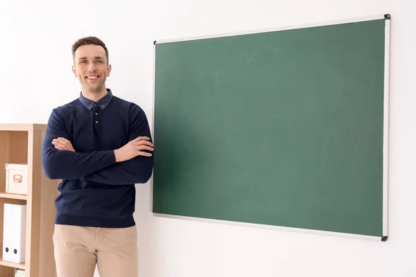 Młody mężczyzna nauczyciel stojący w pobliżu tablica w klasie — Zdjęcie stockowe