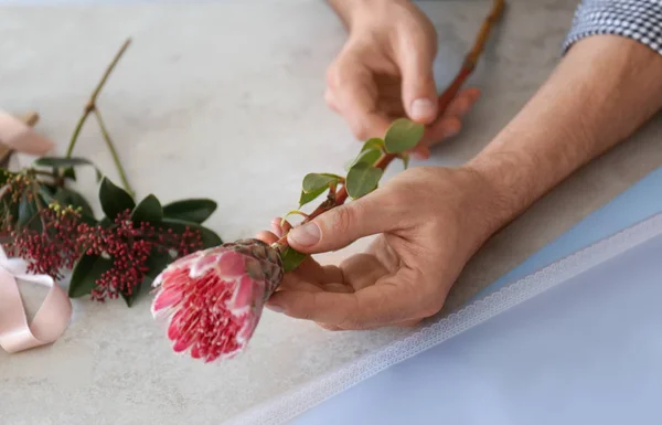 Floristería masculina sosteniendo hermosa flor sobre la mesa, primer plano —  Fotos de Stock