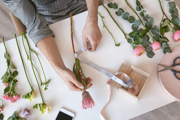 Florista masculino criando belo buquê à mesa, vista superior — Fotografia de Stock