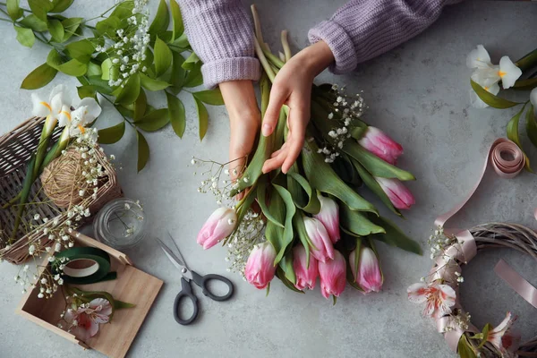 Female decorator creating beautiful bouquet at table