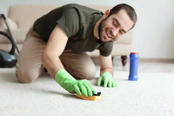 Ung man rengöra mattan hemma — Stockfoto