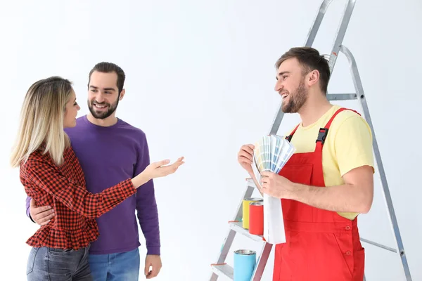 Manliga dekoratör och unga par med färgpaletten på vit bakgrund — Stockfoto