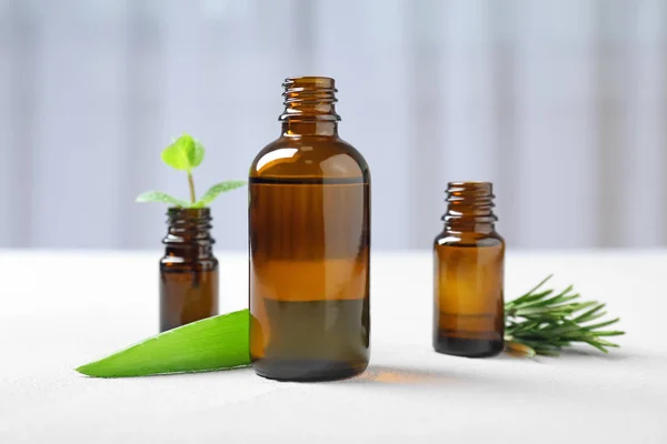 Bottles with essential oils and fresh herbs on table — Stock Photo, Image