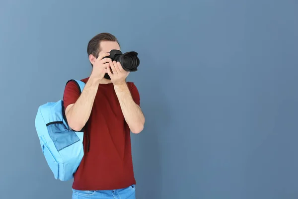 Junger Fotograf mit professioneller Kamera auf farbigem Hintergrund — Stockfoto