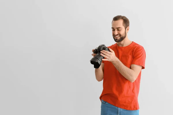 Junger Fotograf mit professioneller Kamera auf weißem Hintergrund — Stockfoto