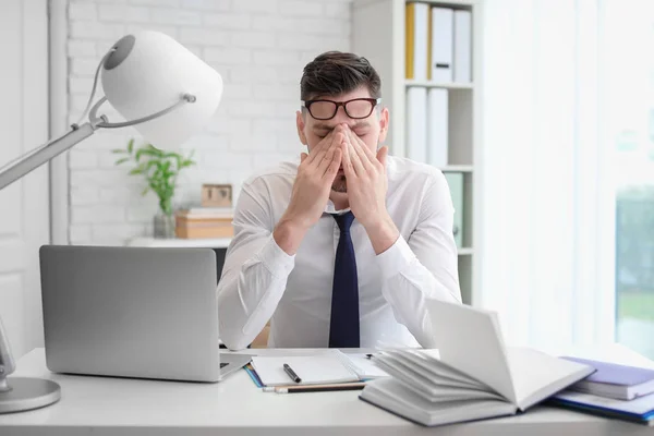 Uomo che soffre di mal di testa mentre è seduto a tavola in ufficio — Foto Stock