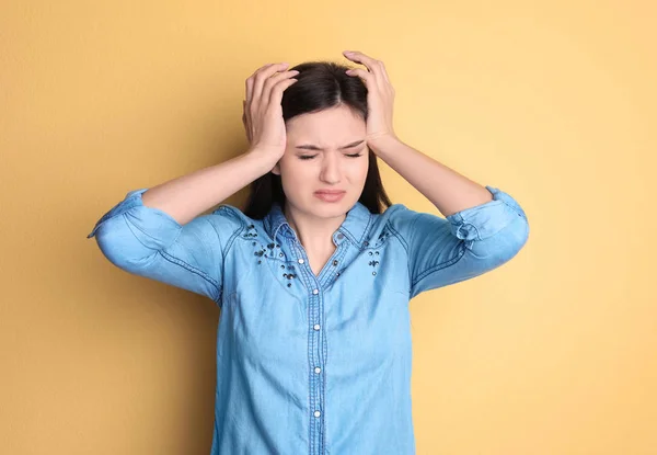 Jonge vrouw lijden aan hoofdpijn op kleur achtergrond — Stockfoto