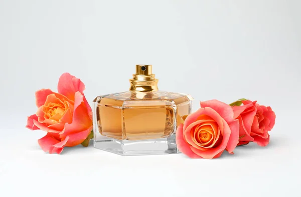 Doorzichtige fles parfum met mooie rozen op witte achtergrond — Stockfoto