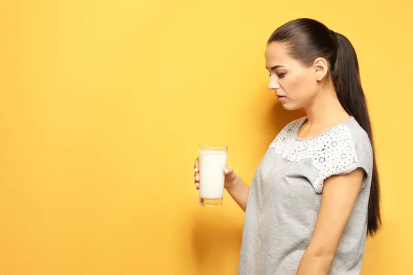 Ung kvinna med mejeri allergi hålla glas mjölk på färgbakgrund — Stockfoto