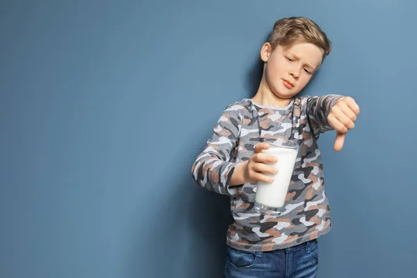 Niño con alergia láctea sosteniendo un vaso de leche sobre fondo de color — Foto de Stock