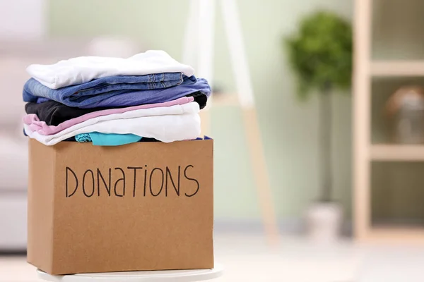 Caja de donación con ropa en la mesa en el interior — Foto de Stock