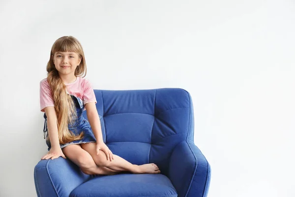 Portrait de mignonne petite fille sur fauteuil contre mur blanc — Photo