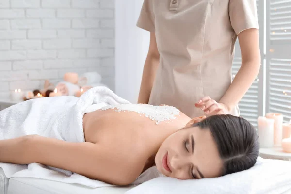 Jovem mulher tendo procedimento de limpeza corporal com sal marinho no salão de spa — Fotografia de Stock