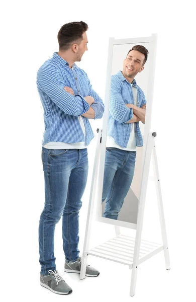 Mladý muž dívá na sebe v zrcadle na bílém pozadí — Stock fotografie