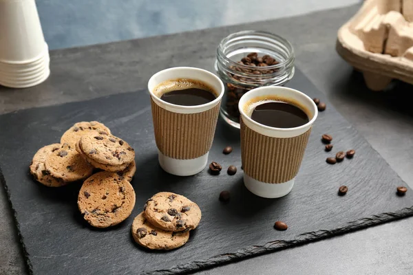 Composição com café quente aromático em copos de papel e biscoitos na mesa — Fotografia de Stock