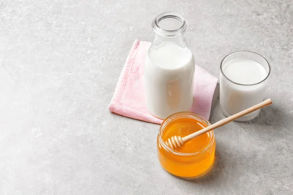 Krásná skladba s mlékem a medem na šedém pozadí — Stock fotografie