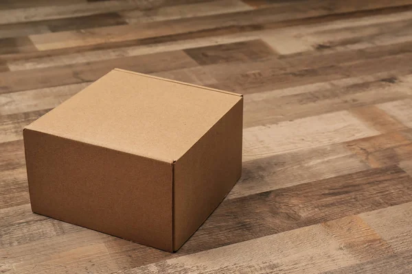 Cardboard box on wooden floor — Stock Photo, Image