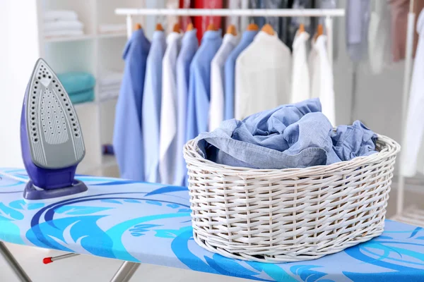 Rieten mand met kleren op strijkplank op droog-cleaner — Stockfoto