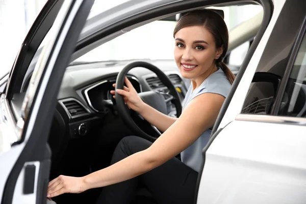 Молода жінка сидить на водійському сидінні нової машини в салоні — стокове фото